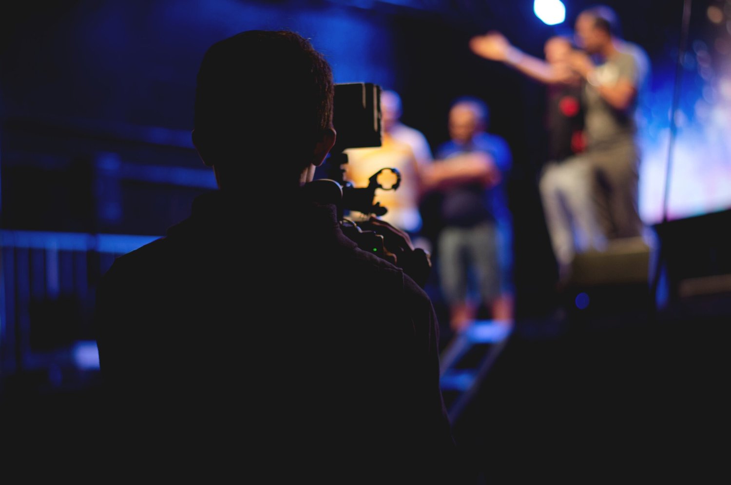 man-standing-on-stage-holding-microphone-1870438.jpg